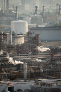 Smoke clouds come out of pipes on refinery factory at sunrise