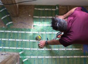WarmlyYours TempZone Flex Rolls Being Installed Over a Wood Subfloor